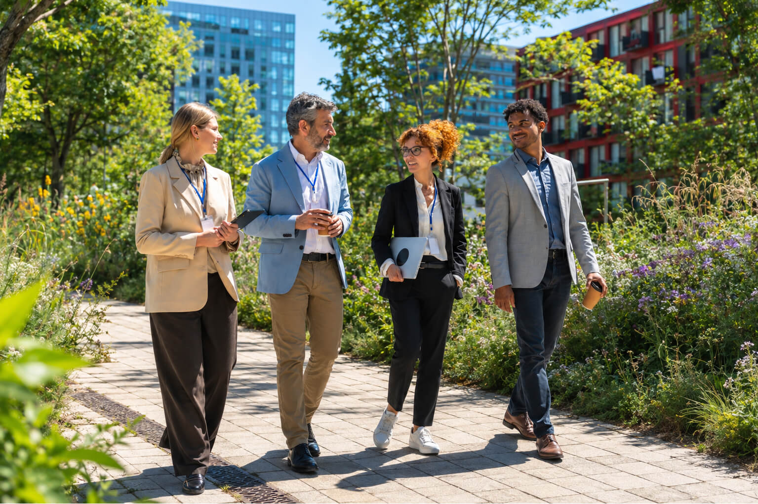 Happy coworkers walking down lush landscaped path while talking.